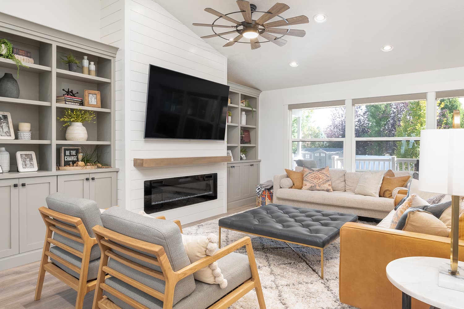 Living area finished by JS ProFinish with custom built-in shelving, shiplap accent wall, and electric fireplace