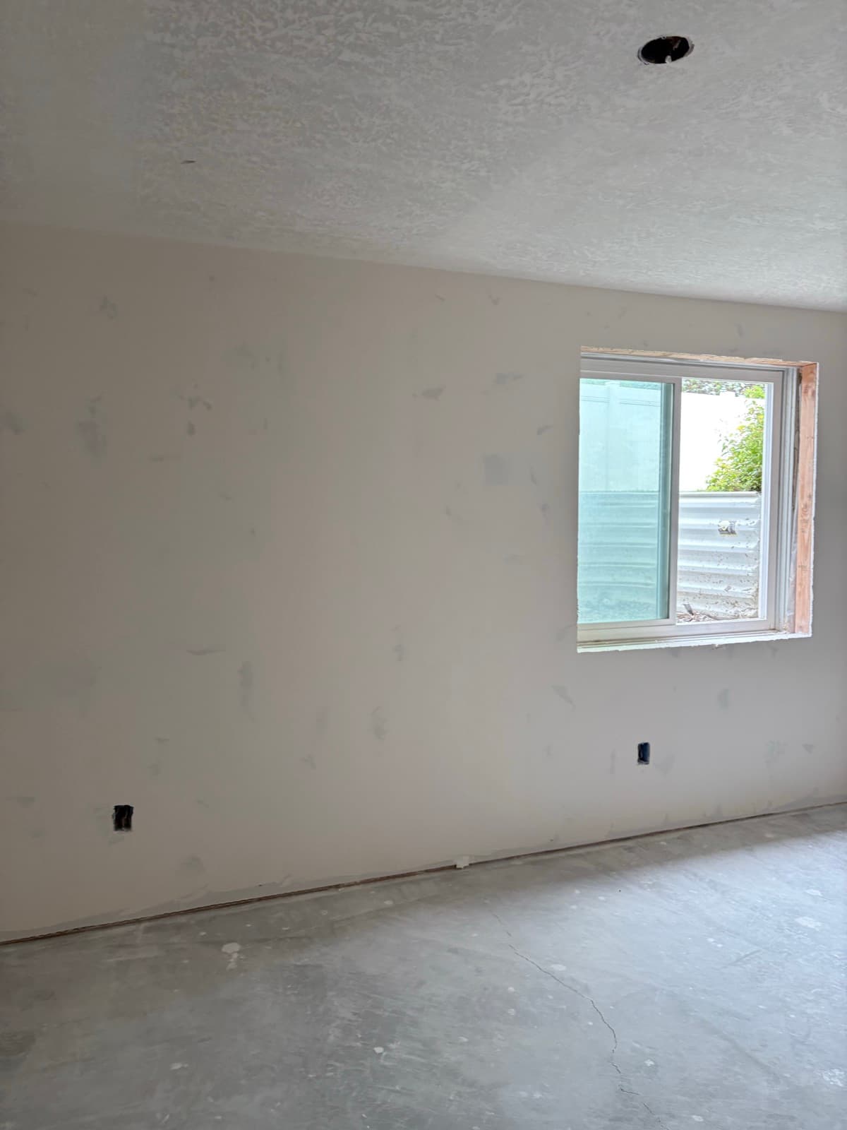 Drywall taped and mudded around a basement window, ready for texture