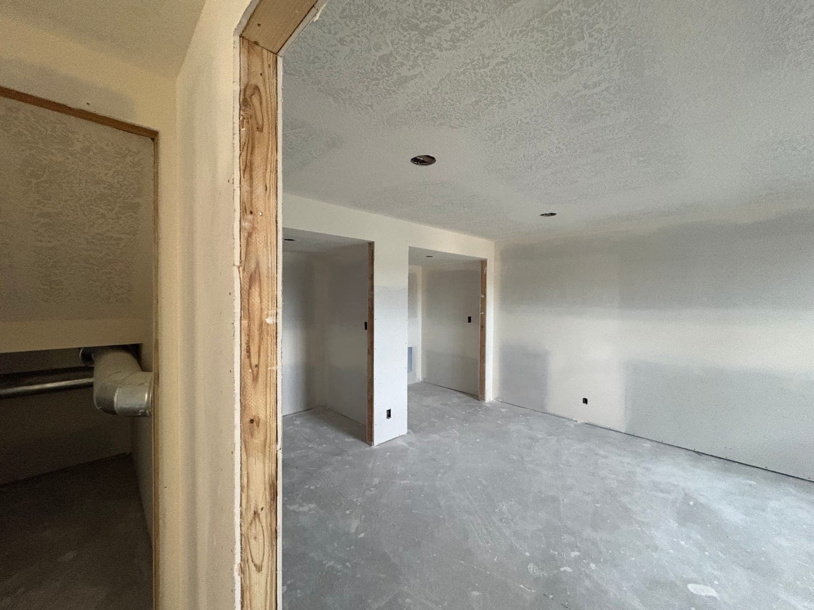 Looking through a bedroom doorway after drywall finishing, before doors and casing