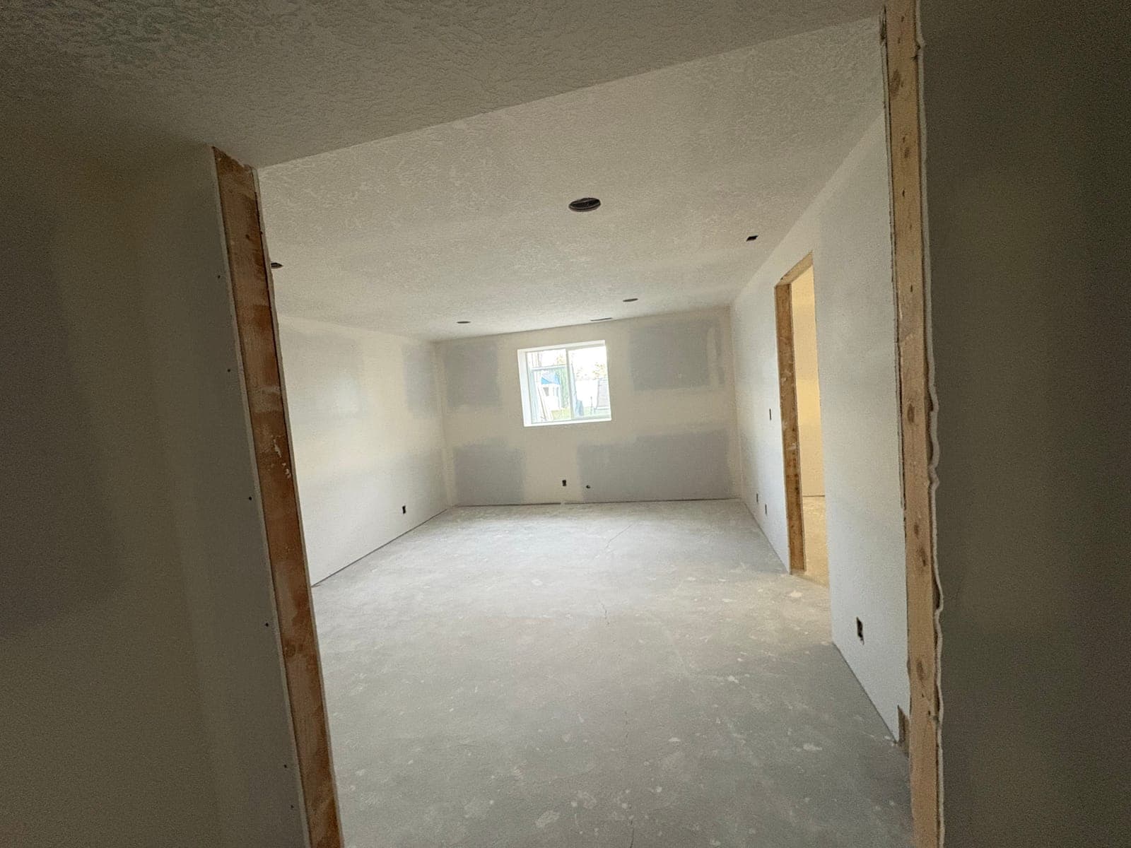 Basement bedroom with taped and textured drywall around the egress window