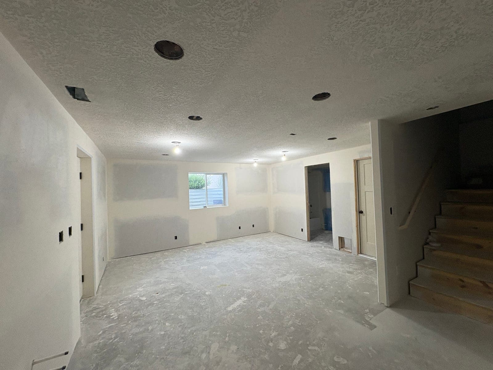 Family room and stairs after tape, mud, and sprayed ceiling texture