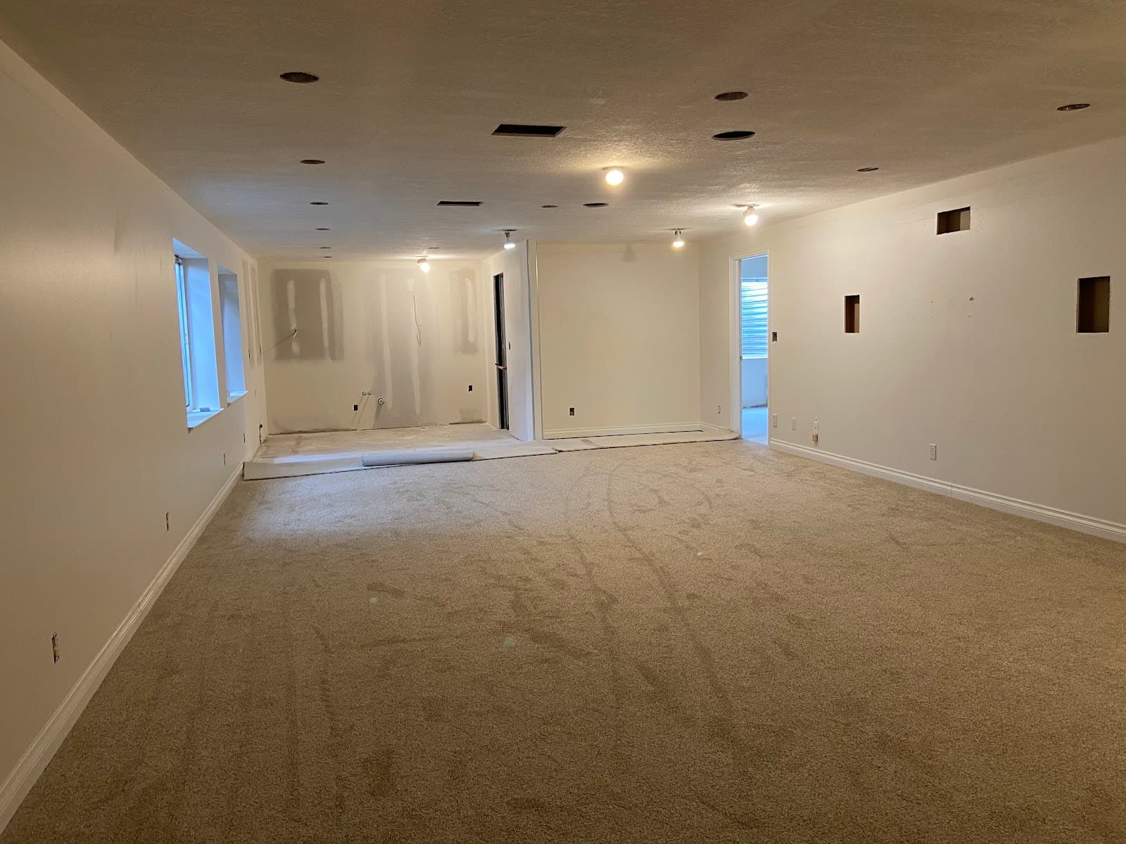 Open basement family room finished with fresh drywall, paint, and carpet by JS ProFinish
