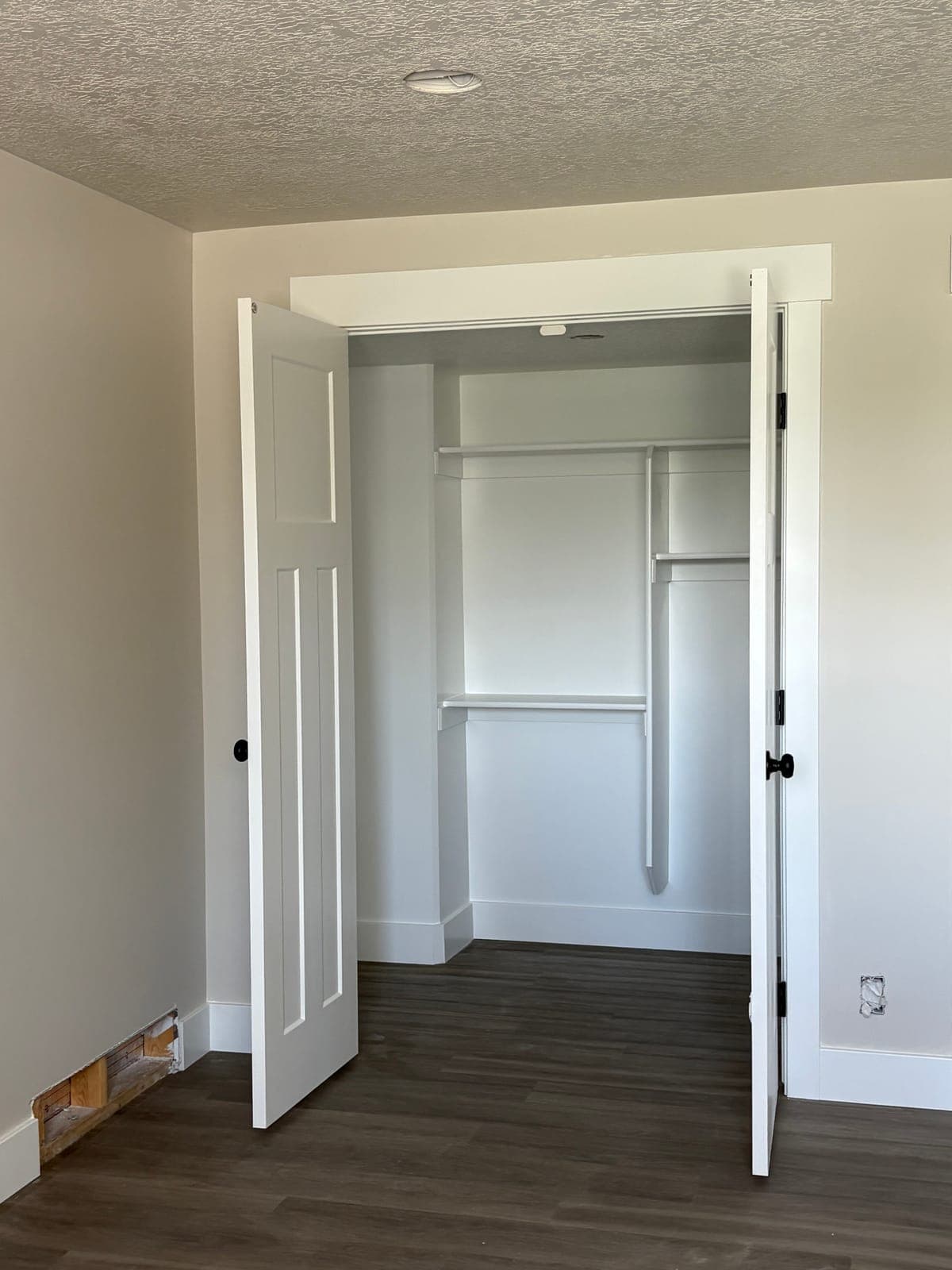 Bi-fold closet open, showing the shelf and hanging rod inside