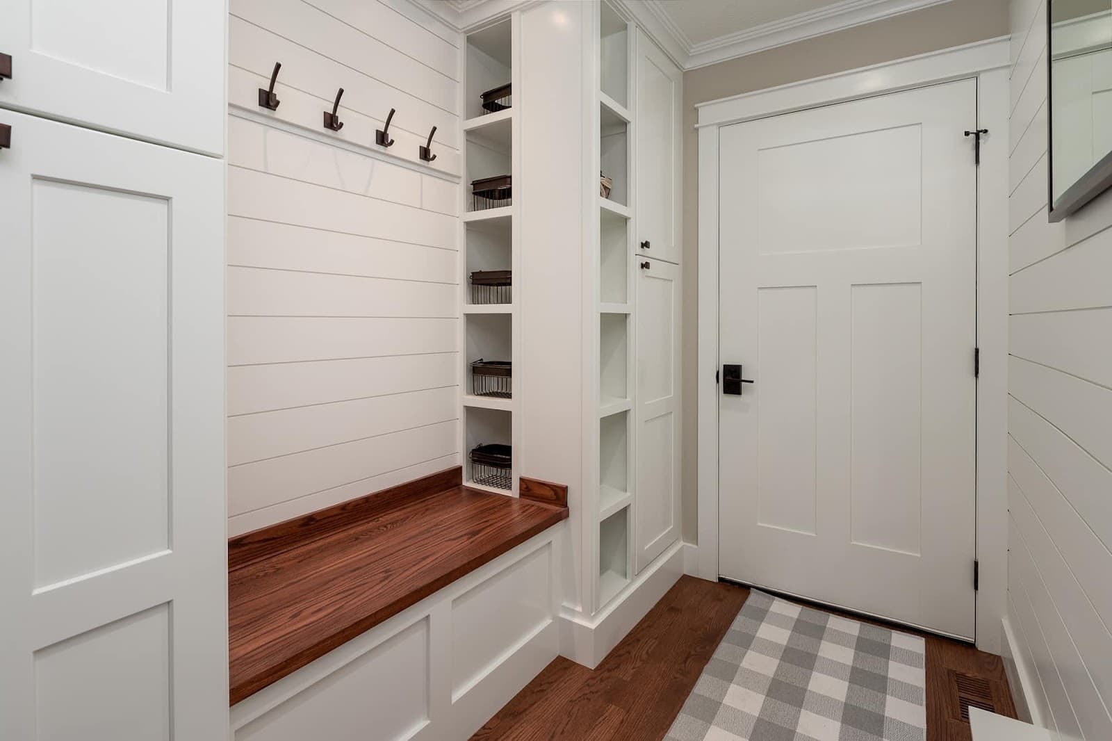 Custom mudroom bench with shiplap wall, coat hooks, and built-in storage cubbies