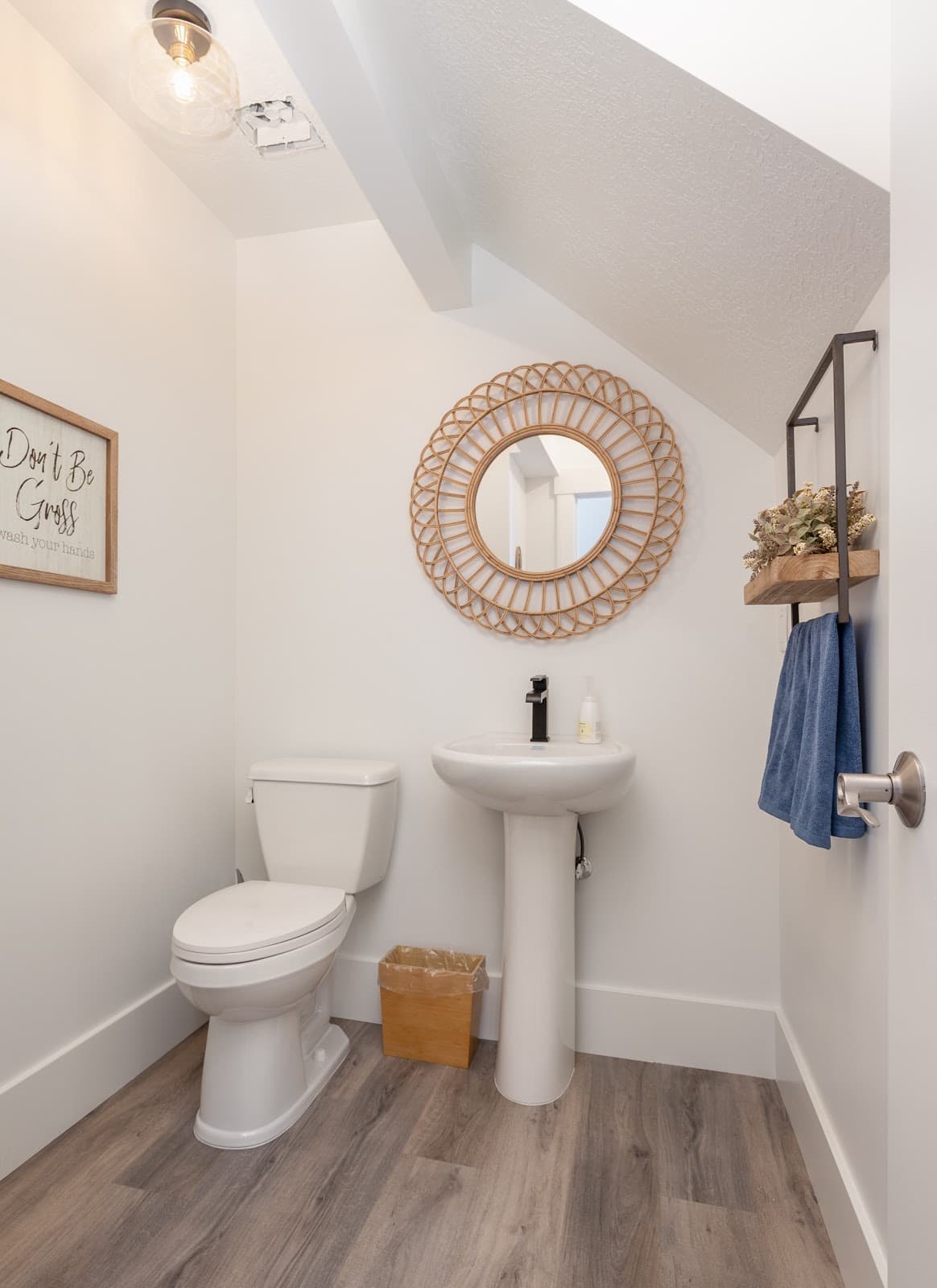 Finished powder bathroom with pedestal sink and round mirror